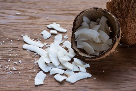 fresh tasty coconut flakes in shell on wooden table