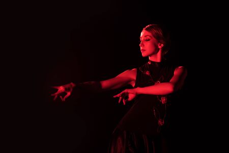 red lighting on beautiful woman dancing flamenco isolated on blackの写真素材