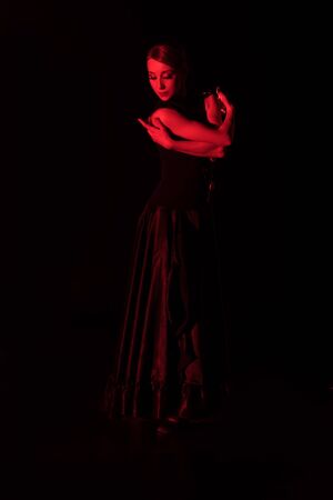 red lighting on elegant woman dancing flamenco isolated on blackの写真素材