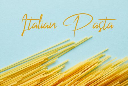 top view of raw spaghetti on blue background with Italian pasta illustrationの写真素材