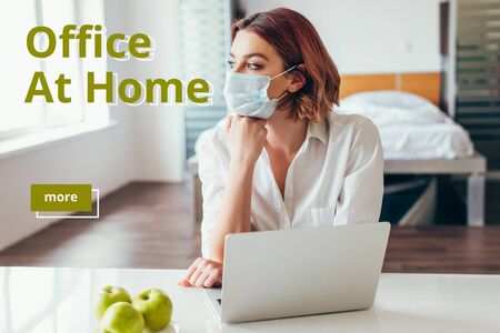 thoughtful freelancer in medical mask working on laptop at home with apples on self isolation with office at home letteringの写真素材