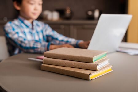 asian boy studying online with laptop and books at home during quarantine, selective focusの写真素材