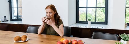 Panoramic shot of woman drinking coffee near croissants on tableの写真素材