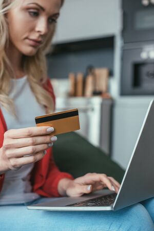 selective focus of young woman using laptop while holding credit cardの写真素材