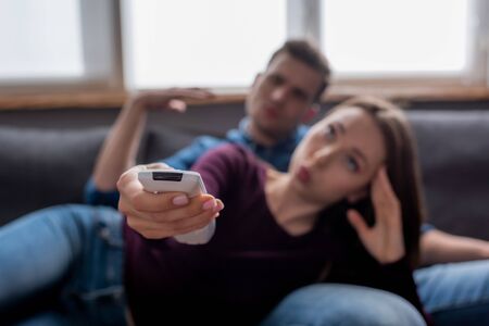 selective focus of man near woman holding remote controller from air conditioner while feeling hotの写真素材