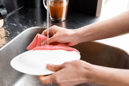 Cropped view of woman washing plate in kitchenの写真素材