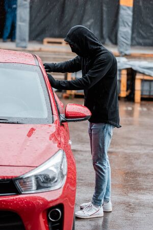 Selective focus of robber stealing car during rain on urban streetの写真素材