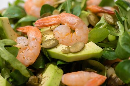 close up view of fresh green salad with pumpkin seeds, shrimps and avocadoの写真素材