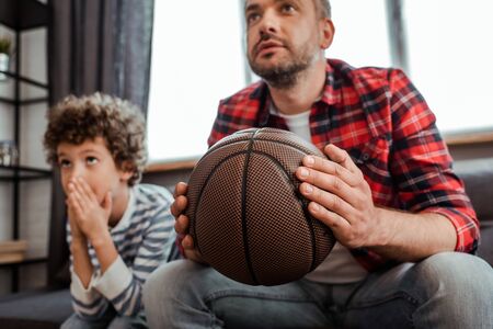 selective focus of father holding basketball while watching championship with sonの写真素材