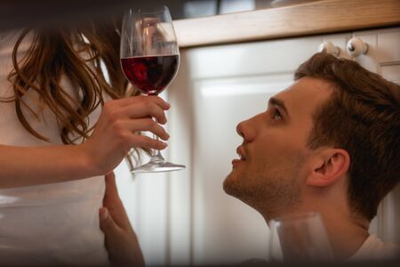 woman holding glass of red wine near handsome manの写真素材