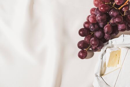 top view of french breakfast with grape and Camembert on textured white tableclothの写真素材