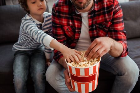 cropped view of kid reaching tasty popcorn near bearded fatherの写真素材