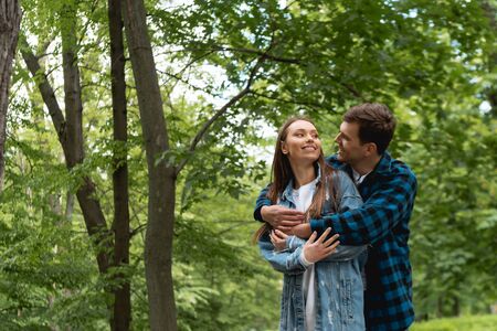 happy student hugging pretty girlfriend in green parkの写真素材