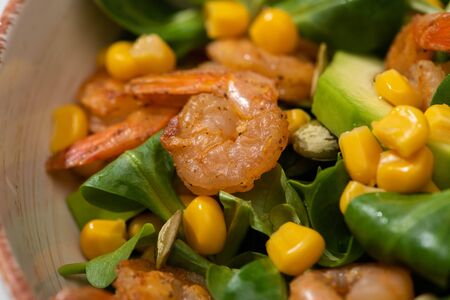 close up view of fresh green salad with pumpkin seeds, corn, shrimps and avocadoの写真素材