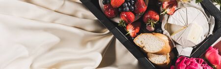 top view of french breakfast with Camembert, berries and baguette on tray on white tablecloth, panoramic shotの写真素材