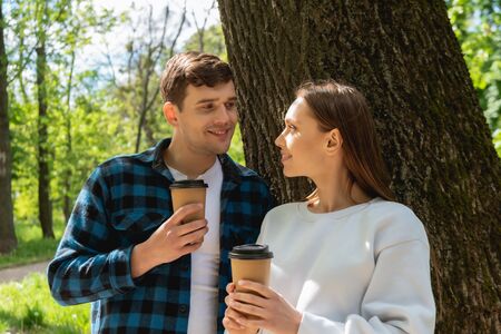 happy students holding paper cups and looking at each other
