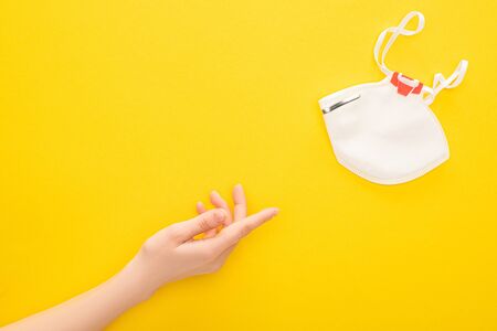 partial view of woman pointing at safety mask on yellow backgroundの写真素材