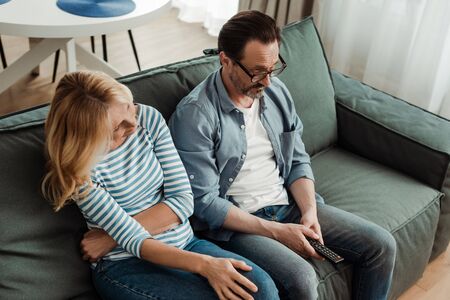 Overhead view of mature couple watching tv on couchの写真素材