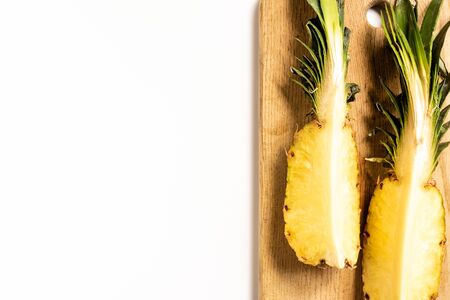 top view of cut juicy pineapple on cutting board on white backgroundの写真素材