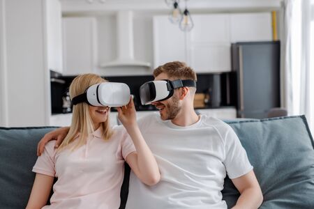 happy couple in virtual reality headsets gaming at home