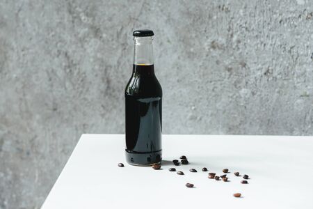 cold brew coffee in bottle near coffee beans on white tableの写真素材