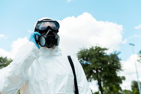 cleaning specialist in hazmat suit and respirator talking on cellphone outdoors during coronavirus pandemicの写真素材