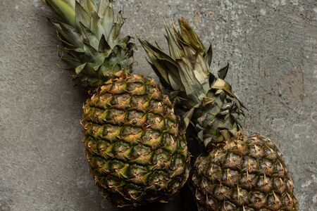 top view of ripe pineapples on grey concrete surfaceの写真素材