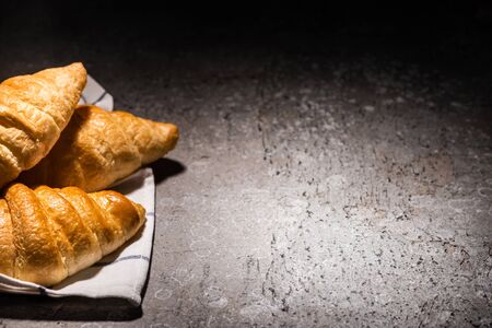 fresh baked croissants on towel on concrete grey surface in darkの写真素材