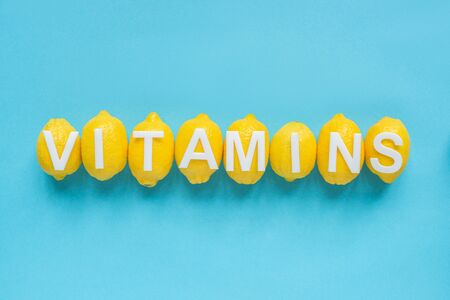 top view of ripe yellow lemons and word vitamins on blue backgroundの写真素材