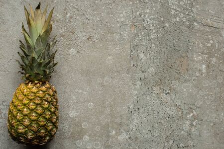 top view of ripe pineapple on grey concrete surface with copy spaceの写真素材