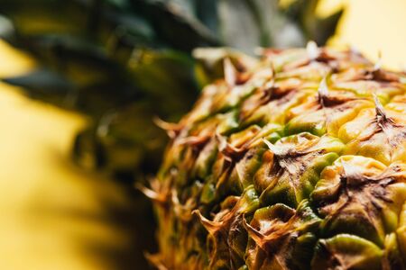 close up view of textured peel of pineapple on yellow backgroundの写真素材