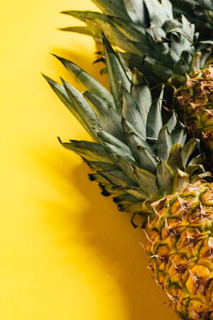 fresh ripe pineapples with green leaves on yellow background