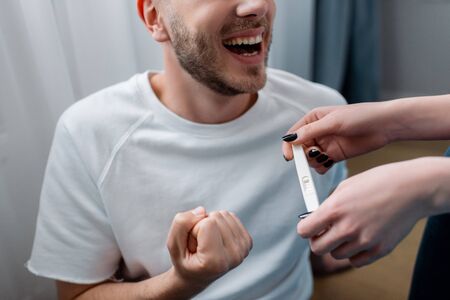 cropped view of girl holding pregnancy test with positive result near happy manの写真素材