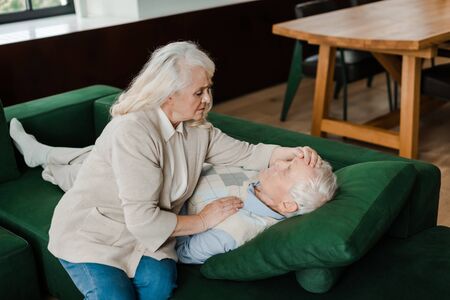 worried senior wife checking husband temperature at home on self isolationの写真素材