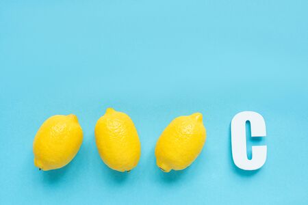 top view of ripe yellow lemons and letter C on blue backgroundの写真素材