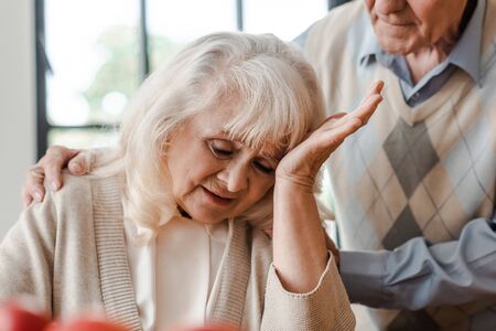 elderly wife having headache at home with husband during self isolation