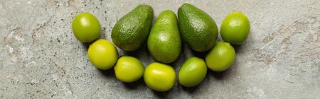 top view of green avocado, limes on grey concrete surface, panoramic shot