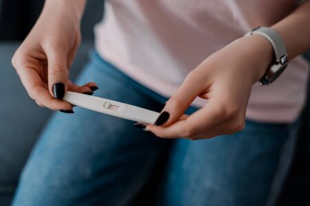 cropped view of girl holding pregnancy test with positive resultの写真素材
