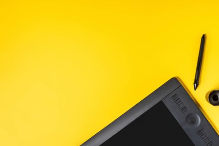 top view of drawing tablet near stylus holder and stylus on yellowの写真素材