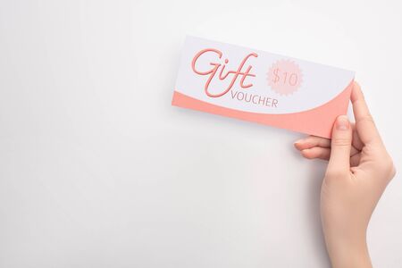 Top view of woman holding gift voucher with 10 dollars sign on white surfaceの写真素材