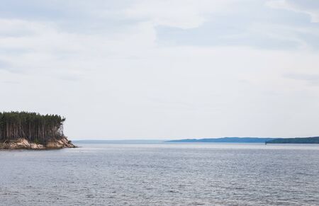 clean lake near green trees against sky with cloudsの写真素材