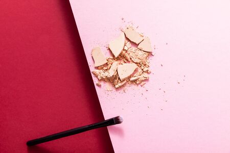 top view of cracked face powder and cosmetic brush on crimson and pinkの写真素材