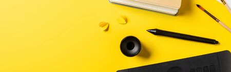 panoramic shot of drawing tablet, holder and stylus on yellow