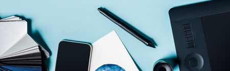Panoramic shot of graphics tablet, smartphone and color samples on blue backgroundの写真素材