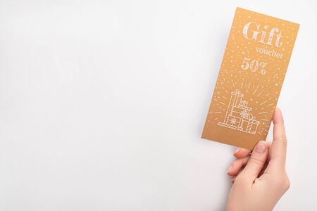 Top view of woman holding golden gift voucher with 50 percents sign on white backgroundの写真素材