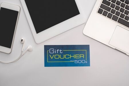 Top view of gift voucher near gadgets on white backgroundの写真素材