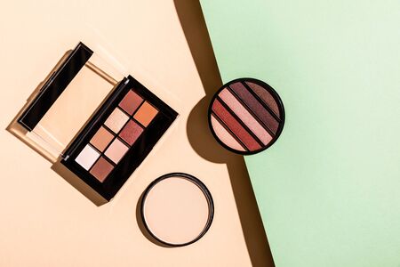 top view of face powder near eye shadow palettes on pink and blueの写真素材