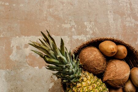 top view of ripe exotic fruits in wicker basket on weathered surfaceの写真素材