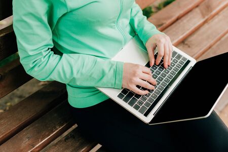 Cropped view of freelancer using laptop on bench on urban streetの写真素材