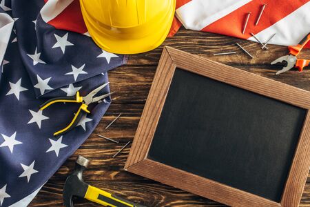 top view of american flag and instruments near blank chalkboard on wooden surface, labor day concept